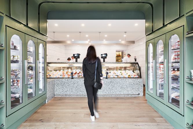 A customer at the counter, with butchers working behind it.